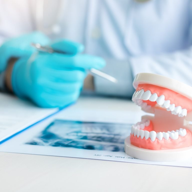 Close up dentures with dentist working on table in clinic.